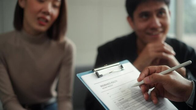 Close-up of a health questionnaire being filled out by a married couple
with an insurance agent. Financial planning for life insurance, health
coverage and retirement insurance.