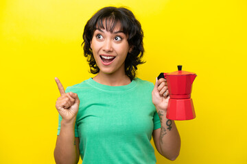 Obraz premium Young Argentinian woman holding coffee pot isolated on yellow background intending to realizes the solution while lifting a finger up