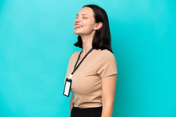 Young caucasian woman with ID card isolated on blue background laughing in lateral position