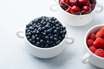 Bowls of raspberries, blueberries and cherries for fruit trio, diet or nutrition concept