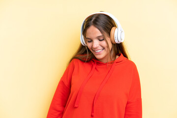 Young caucasian woman isolated on yellow background listening music