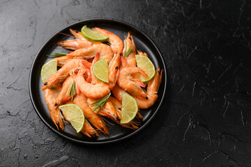 Bowl of cooked shrimp with lime on black background for seafood restaurant or gourmet menu concept