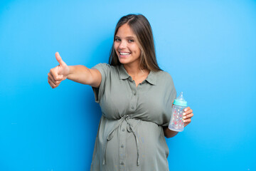 Pregnant woman on blue background giving a thumbs up gesture