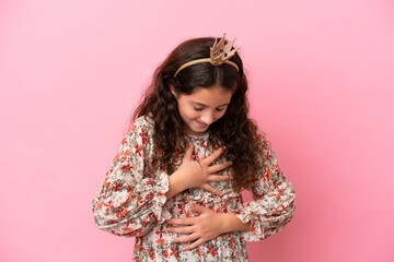 Little caucasian princess with crown isolated on pink background smiling a lot