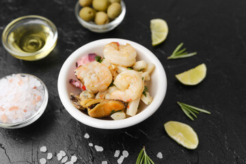 seafood bowl with lime and herbs on black table for minimalist gourmet or ingredient styling concept