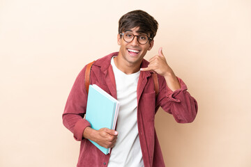 Young student caucasian man isolated on ocher background making phone gesture. Call me back sign