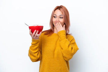 Young Russian girl holding a bowl of cereales isolated on white background with surprise and...