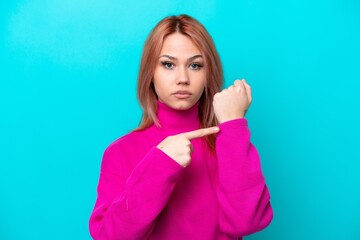 Young Russian woman isolated on blue background making the gesture of being late