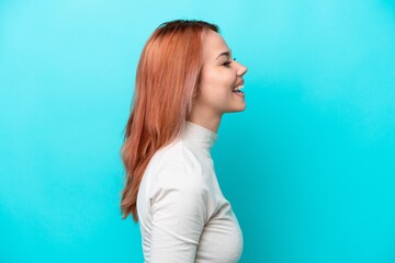 Young Russian woman isolated on blue background laughing in lateral position