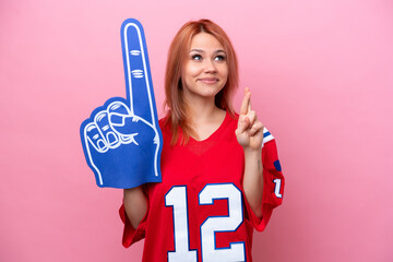 Young Russian rugby fan girl isolated on pink background with fingers crossing and wishing the best