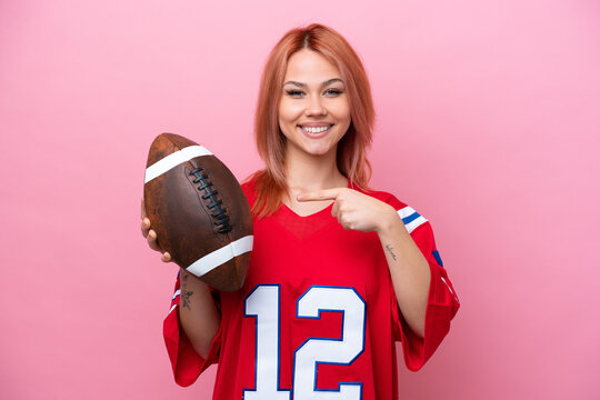 Young Russian girl playing rugby isolated on pink background and pointing it