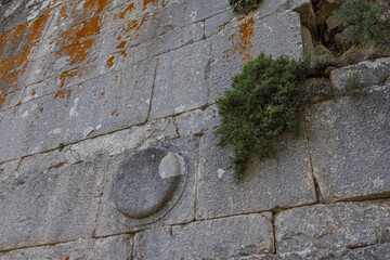 Termessos is an ancient city located in Turkey high in the mountains. The walls of the buildings in the ancient city are made of large smooth stone blocks. A round symbol is carved on the block.