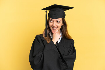 Young university graduate isolated on yellow background looking to the side and smiling