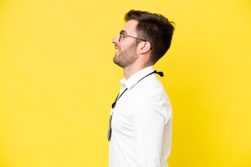 Young caucasian with ID card isolated on yellow background laughing in lateral position