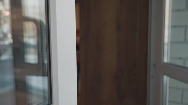 close up of young lady in denim jeans stepping out from mall holding book while pulling glass door handle, captured in natural light highlighting motion and urban style in commercial entryway