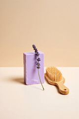 Purple lavender soap bar with fresh lavender sprig and wooden brush on neutral background.