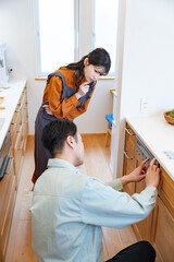 キッチンを確認する業者と悩む主婦