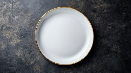 Empty white plate with gold rim on dark stone background.
