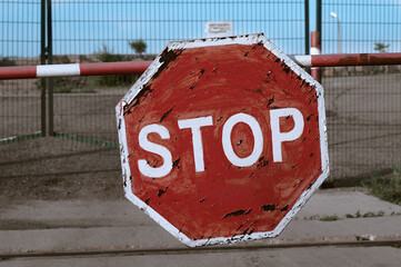 Old Red Stop Sign on a barrier. No entry. Rust and scratches on the road sign.