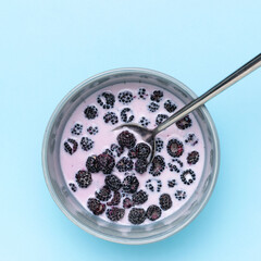 Top View of Fresh Blackberries in Yogurt with Spoon on Blue Background