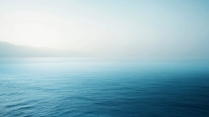 Obraz premium Serene ocean scene at dawn, calm water, hazy horizon, peaceful atmosphere.