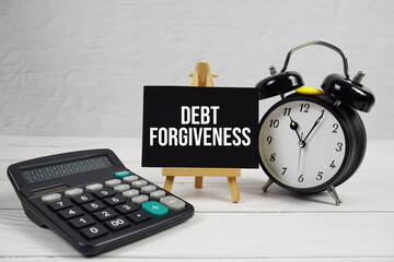 Debt Forgiveness text with alarm clock on wooden background