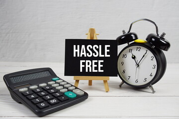 Hassle Free text with alarm clock on wooden background