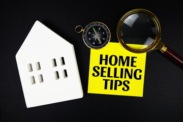 Home Selling Tips text message with white house model and magnifying glass top view on black...