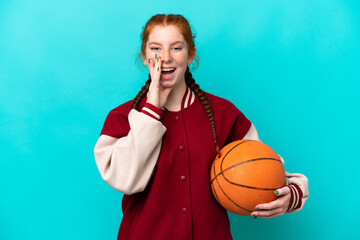 Young reddish woman playing basketball isolated on blue background shouting with mouth wide open