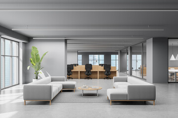 Modern open office interior with lounge area, minimalist furniture, and large windows in a bright...