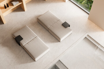 Minimalist modern interior with beige loungers and built-in wooden shelving beside a large window...
