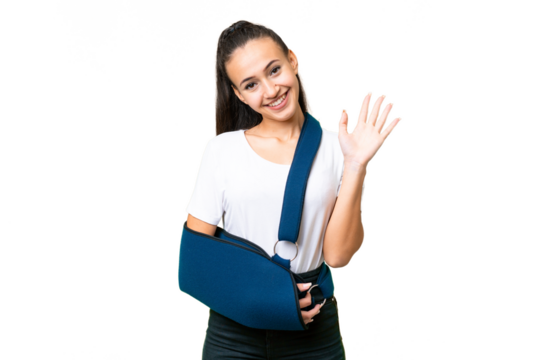 Young Arabian woman with broken arm and wearing a sling over isolated chroma key background saluting with hand with happy expression