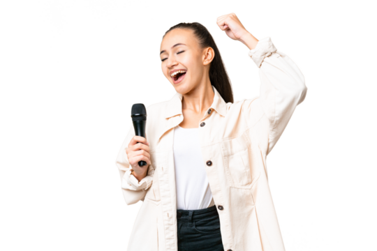 Young singer woman picking up a microphone over isolated chroma key background celebrating a victory - Powered by Adobe