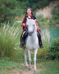 Asian Teen Tourist Girl Enjoys Horseback Riding in Modern Hill Tribe Costume in Chiang Mai,...