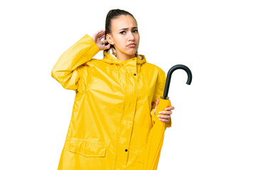 Young Arabian woman with rainproof coat and umbrella over isolated chroma key background having...