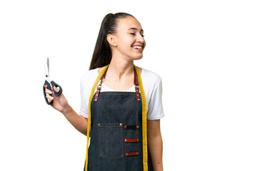Young Seamstress woman over isolated chroma key background laughing in lateral position