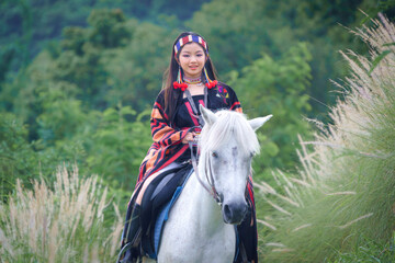 Asian Teen Tourist Girl Enjoys Horseback Riding in Modern Hill Tribe Costume in Chiang Mai,...