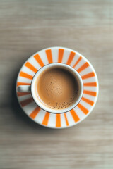 Exquisite coffee served in a striped cup on a light wooden table in a cozy cafe