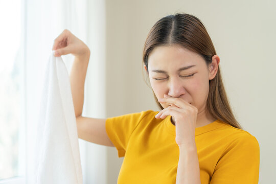 Young people doing laundry smelling for dirty clothes.