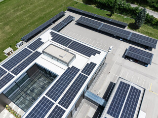 Aerial view of building with solar panels on a roof and parking space with solar canopies