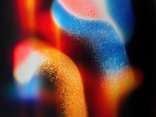 Abstract grunge film grain texture with colorful vintage light leaks on dark background, retro blurry orange blue red streaks for design elements overlay.​