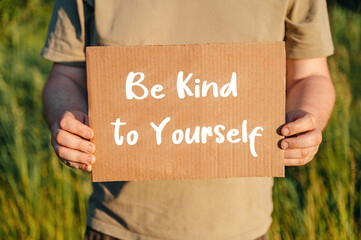 man with a sign be kind to yourself