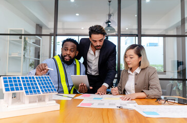 team of multiethnic coworker meeting on solar roof system project with solar panel house model,...
