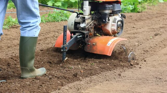 Latin farmer woman plowing soil with orange cultivator