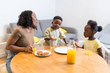 Happy family eating breakfast at home, mother and children enjoying meal together