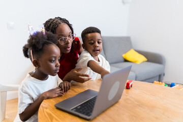Mother helping children using laptop at home