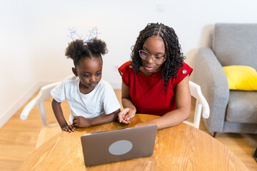 Mother and daughter using laptop at home