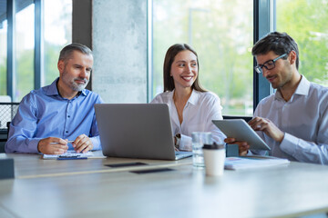 Successful businesspeople working in a coworking space working with laptop discussing strategy and...