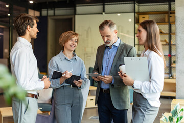 Group of business people standing together and discussing their work and projects, having a team...