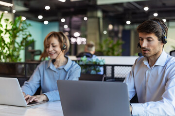 Two business people using laptop on desk discussing strategy company with other employees on...